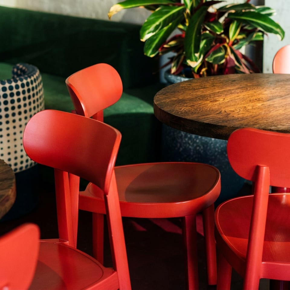 Vibrant red chairs and wooden tables in a modern restaurant interior with green sofa seating.